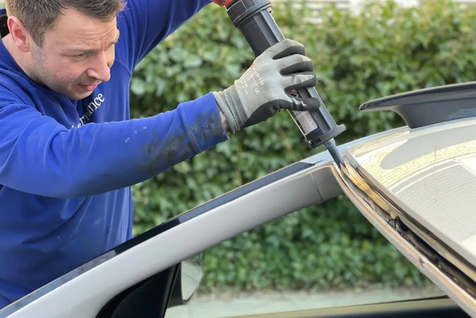 Technicien appliquant une résine sur un impact en étoile au pare-brise d'une voiture en atelier